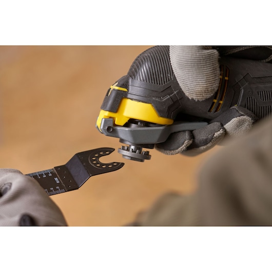STANLEY SFMCE500D2K oscillating tool close-up with blade attachment held by gloved hands.