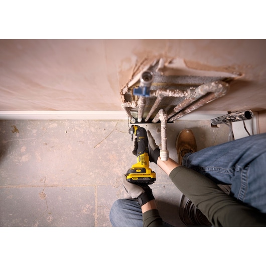 STANLEY SFMCE500D2K oscillating multi-tool used for pipe maintenance in a home setting, top view photography.