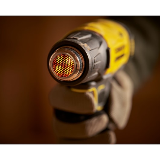 STANLEY SFMCE530B heat gun close-up showing heated metal nozzle held by gloved hand, product photography.