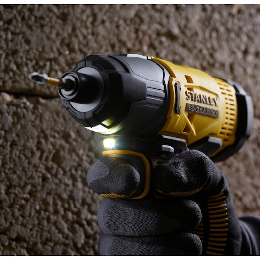STANLEY SFMCF800C2K cordless impact driver in use against concrete wall, close-up view with LED light on.