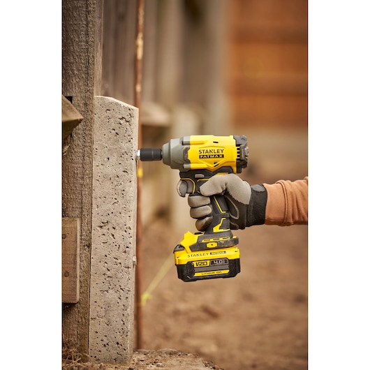 STANLEY SFMCF920B impact driver in use, yellow and black, outdoor close-up, photography category.