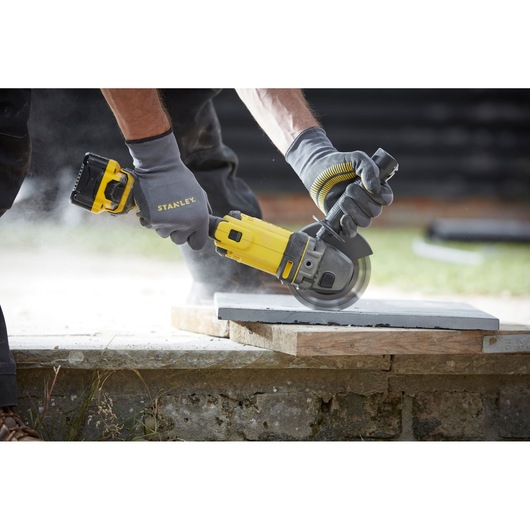STANLEY SFMCG400M2K cordless angle grinder in use cutting concrete, close-up outdoors.