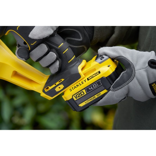 Stanley SFMCHT855B brushless trimmer close-up with V20 4.0Ah battery, yellow and black design.