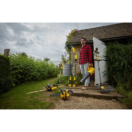 STANLEY SFMCHT855B garden tool collection with yellow-black hedge trimmer, chainsaw, blower, and grass trimmer outdoors.