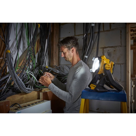 Stanley SFMCL030B work light illuminating electrician working amid cables in unfinished wall.