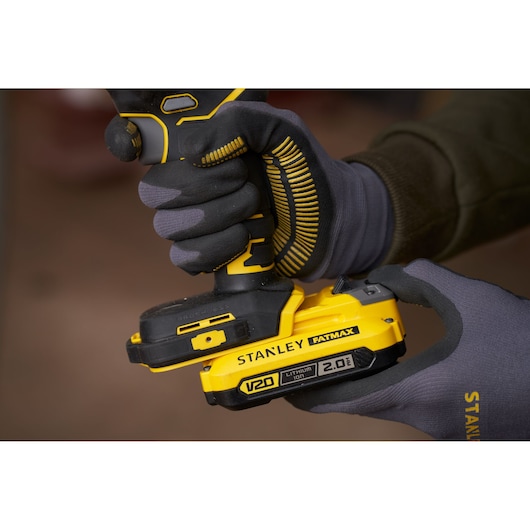 Photo of STANLEY SFMCS305B power tool with yellow V20 2.0Ah battery held by gloved hands.