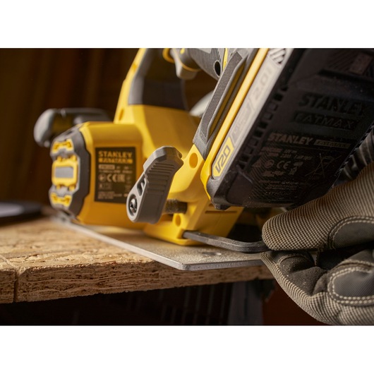 Photo of STANLEY SFMCS550B cordless jigsaw cutting wood, close-up angle showing battery and grip.