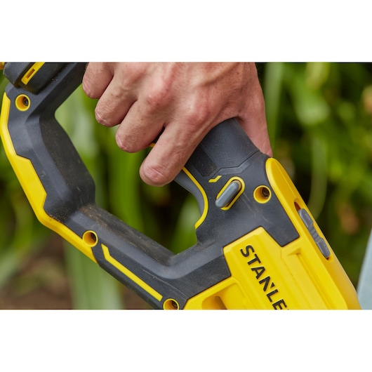Photo of STANLEY SFMCST933B power tool handle in yellow and black, close-up with hand holding grip.
