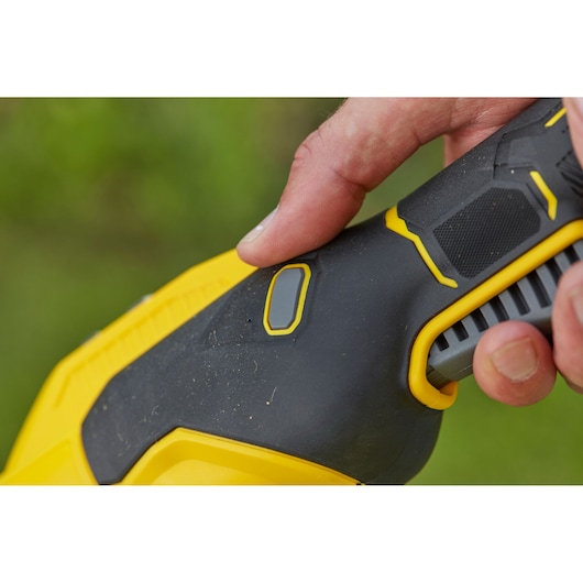 STANLEY SFMCSTB933B power tool handle in black and yellow with finger pressing the button, close-up photo.