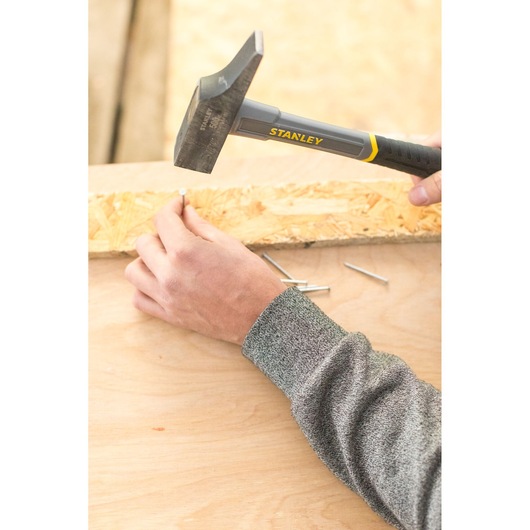 STANLEY STHT0-54160 claw hammer driving nail into wood, close-up photography.