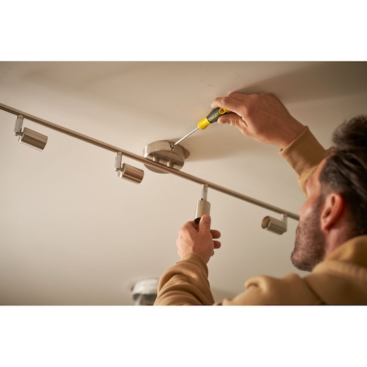 STANLEY STHT0-60276 screwdriver used to install ceiling light fixture, product in hand, close-up.