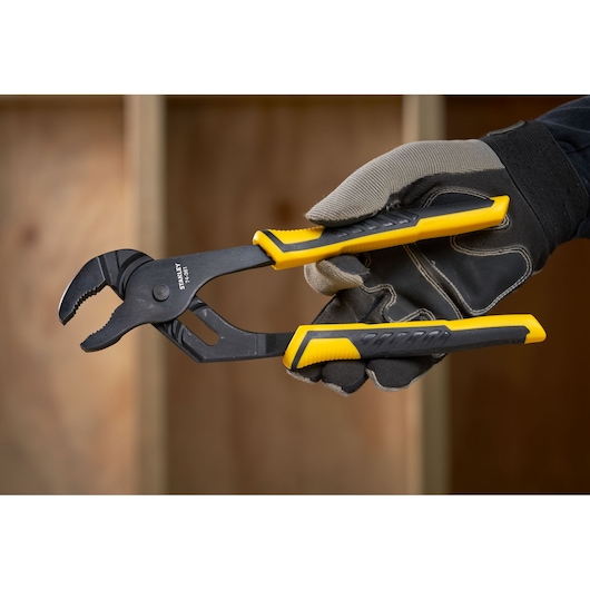 Photo of STANLEY STHT0-74361 adjustable pliers with yellow and black handles, held by a gloved hand.