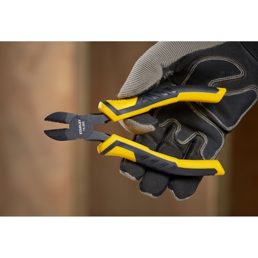 STANLEY STHT0-74362 diagonal cutting pliers with yellow and black handles held by a gloved hand.
