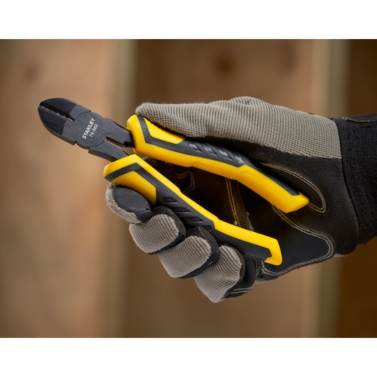 STANLEY STHT0-74362 diagonal cutting pliers with yellow handles held in gloved hand, close-up.