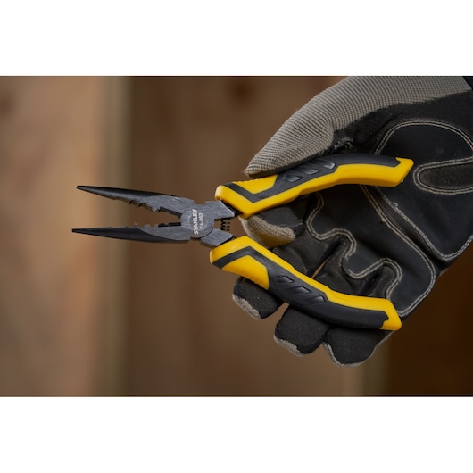 Photo of STANLEY STHT0-74363 pliers with yellow and black handles held by a gloved hand.