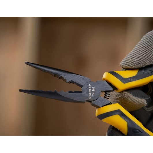 STANLEY STHT0-74364 pliers with yellow and black handles held in a gloved hand, close-up photography.