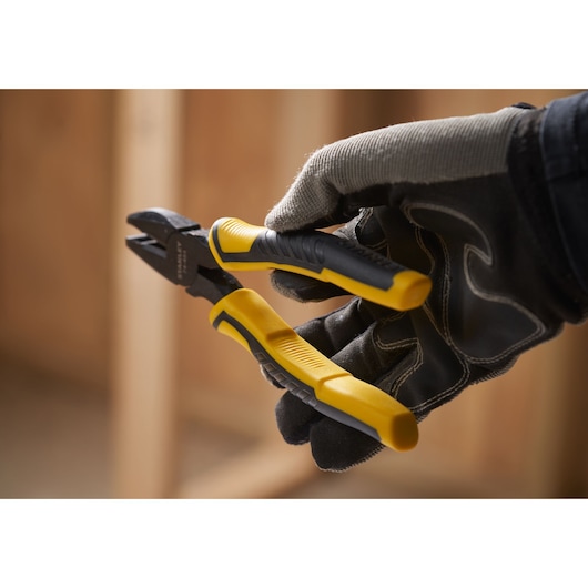 STANLEY STHT0-74456 yellow and black diagonal cutting pliers held by gloved hand, side angle.