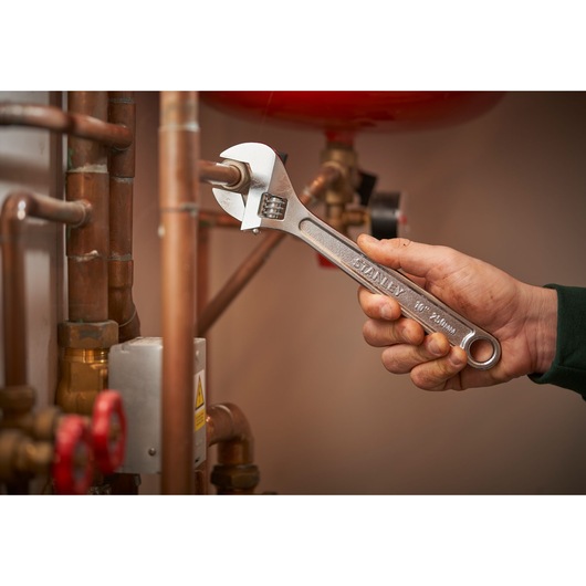 STANLEY STHT13121-0 adjustable wrench used on copper pipes, product held in hand.