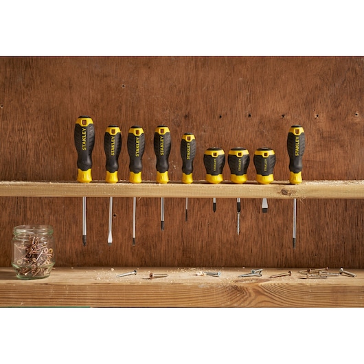 Photo of STANLEY STHT16147-0 screwdriver set, eight black and yellow screwdrivers with ergonomic handles on a workshop shelf.