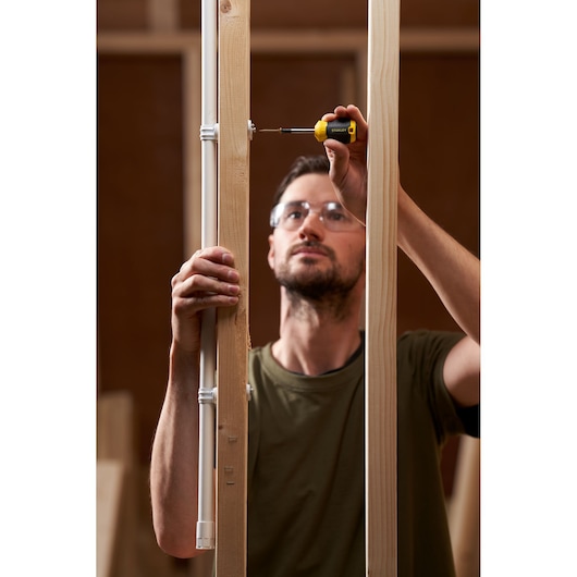 Photo of STANLEY STHT16154-0 screwdriver used to fasten screw in wood frame, indoor construction setting.