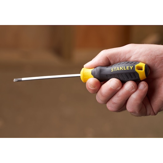 Photo of STANLEY STHT16195-0 screwdriver with yellow and black handle, held in hand, side view.