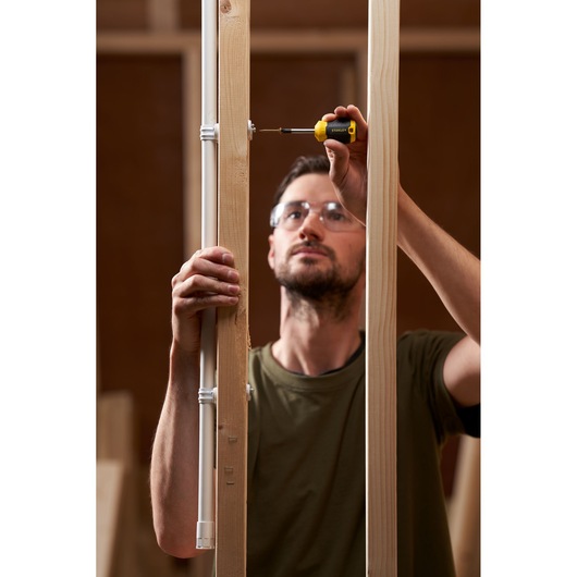 Photo of STANLEY STHT16196-0 screwdriver used by person installing a screw in wooden frame.