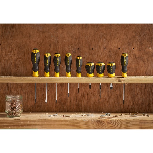 STANLEY STHT16196-0 screwdriver set in black and yellow on shelf, front angle, jar and screws nearby.