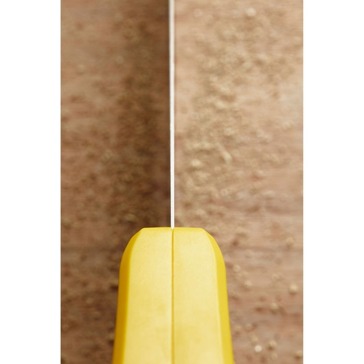STANLEY STHT20350-1 hand saw with yellow handle, front angle, cutting through wood with sawdust visible.
