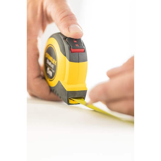 Photo of STANLEY STHT36803-0 tape measure in use, yellow and black, close-up angle.