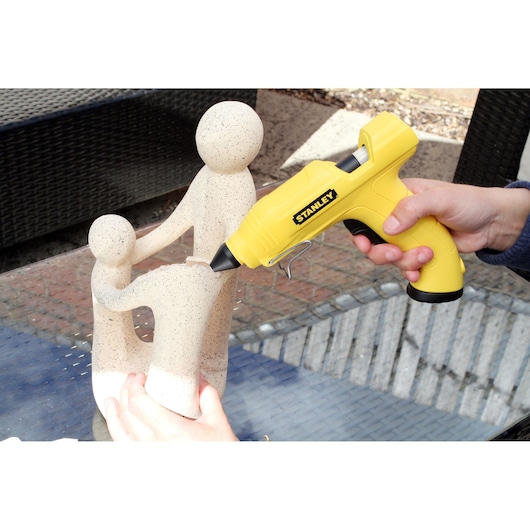 STANLEY STHT6-70416 yellow glue gun used to repair stone sculpture, side angle, photography product.