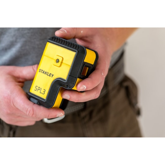 Photo of STANLEY SPL3 STHT77503-1 yellow and black laser level held in hand, front view.