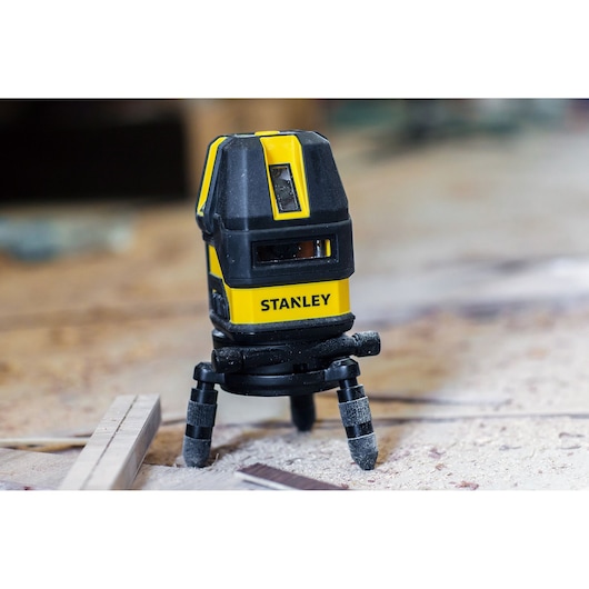 STANLEY STHT77514-1 yellow and black laser level on tripod, shown in a construction setting.