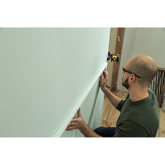STANLEY STHT77592-1 laser level projecting green line for wall trim installation.