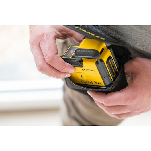 Photo of STANLEY STHT77640-1 CROSS 360° laser level being placed into a black carrying pouch by hand.