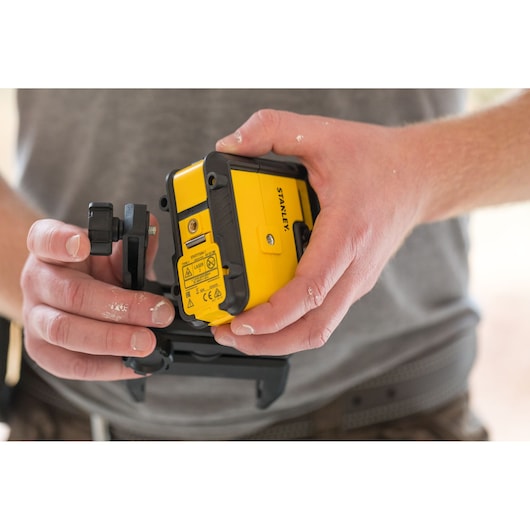 Stanley STHT77641-1 yellow laser level held in hands, close-up view, photography product category.