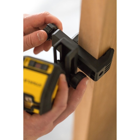 Close-up photo of STANLEY STHT77648-1 laser level being adjusted on a wooden surface clamp.