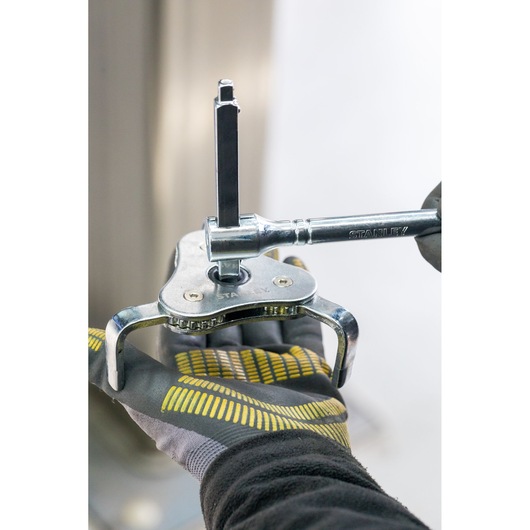 STANLEY STHT80880-0 adjustable three-jaw puller tool in use, close-up showing gloved hand.