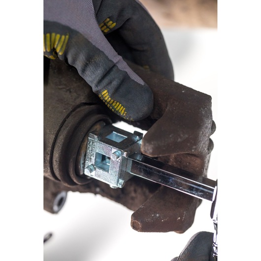 Photo of STANLEY STHT80883-0 brake caliper tool in use, close-up on automotive part with gloved hand.