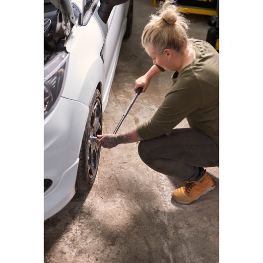 STANLEY STHT80890-0 torque wrench used on a car wheel by a person in a workshop.