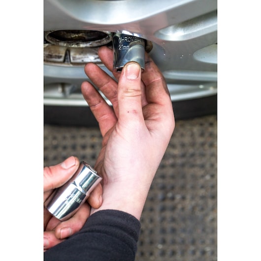 STANLEY STHT80890-0 socket being used to remove a car wheel nut, close-up hand view.