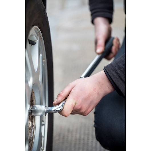 STANLEY STHT80890-0 wrench in use loosening a car wheel nut, close-up angle, automotive hand tool.