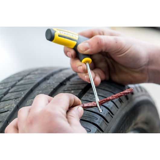 STANLEY STHT80891-0 tire repair tool used to insert plug in car tire, close-up photo.