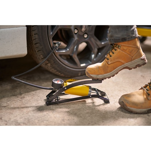 STANLEY STHT80894-1 foot pump inflating car tire, yellow and black, photography of product in use.