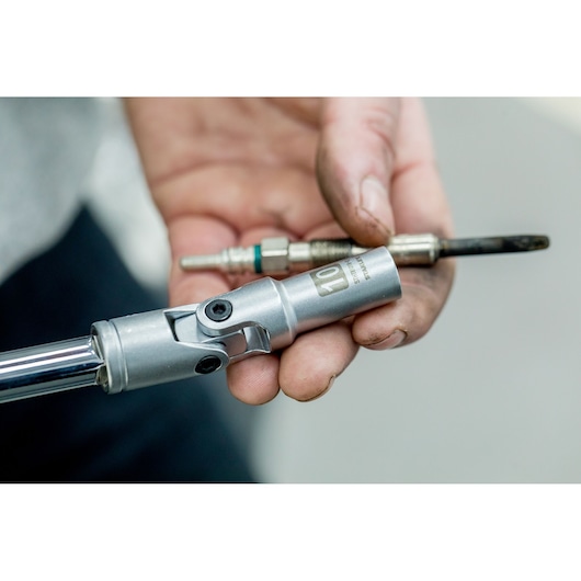 STANLEY STHT81016-0 socket wrench in hand with spark plug, close-up photography of automotive tool.