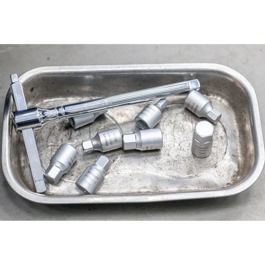 STANLEY STHT81579-0 socket wrench and hex sockets in metal tray, close-up view.