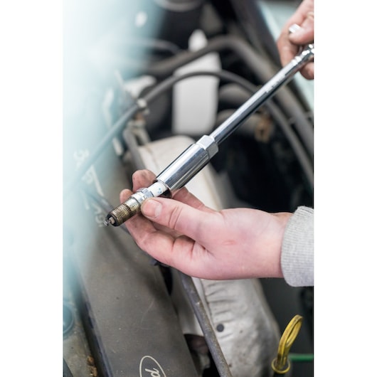 STANLEY STHT81582-0 photography of hand using socket wrench to remove spark plug from engine.