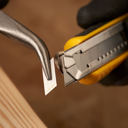 STANLEY STHT9-11301 utility knife close-up, metal blade extended, being removed with pliers, photography.