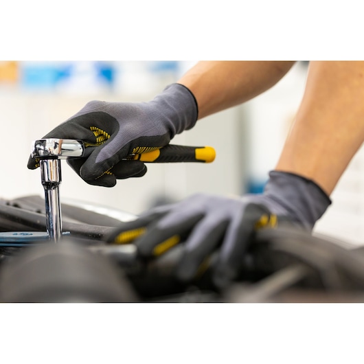 STANLEY STMT82830-1 ratchet wrench in use, close-up, black and yellow handle, mechanic gloves.