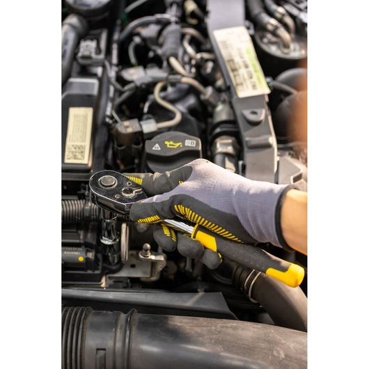 STANLEY STMT82830-1 ratchet wrench held by gloved hand, automotive engine maintenance.