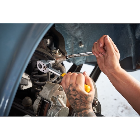 Photo of STANLEY STMT82843-0 combination wrench in use on car part, visible hand holding wrench.